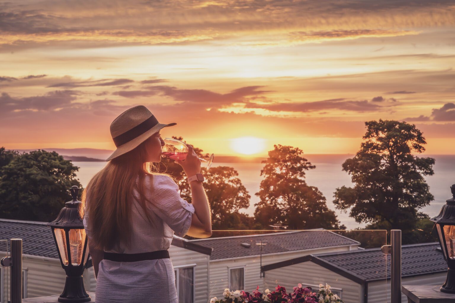 Woman in hat enjoying a drink at sunset at Craiglwyd Hall