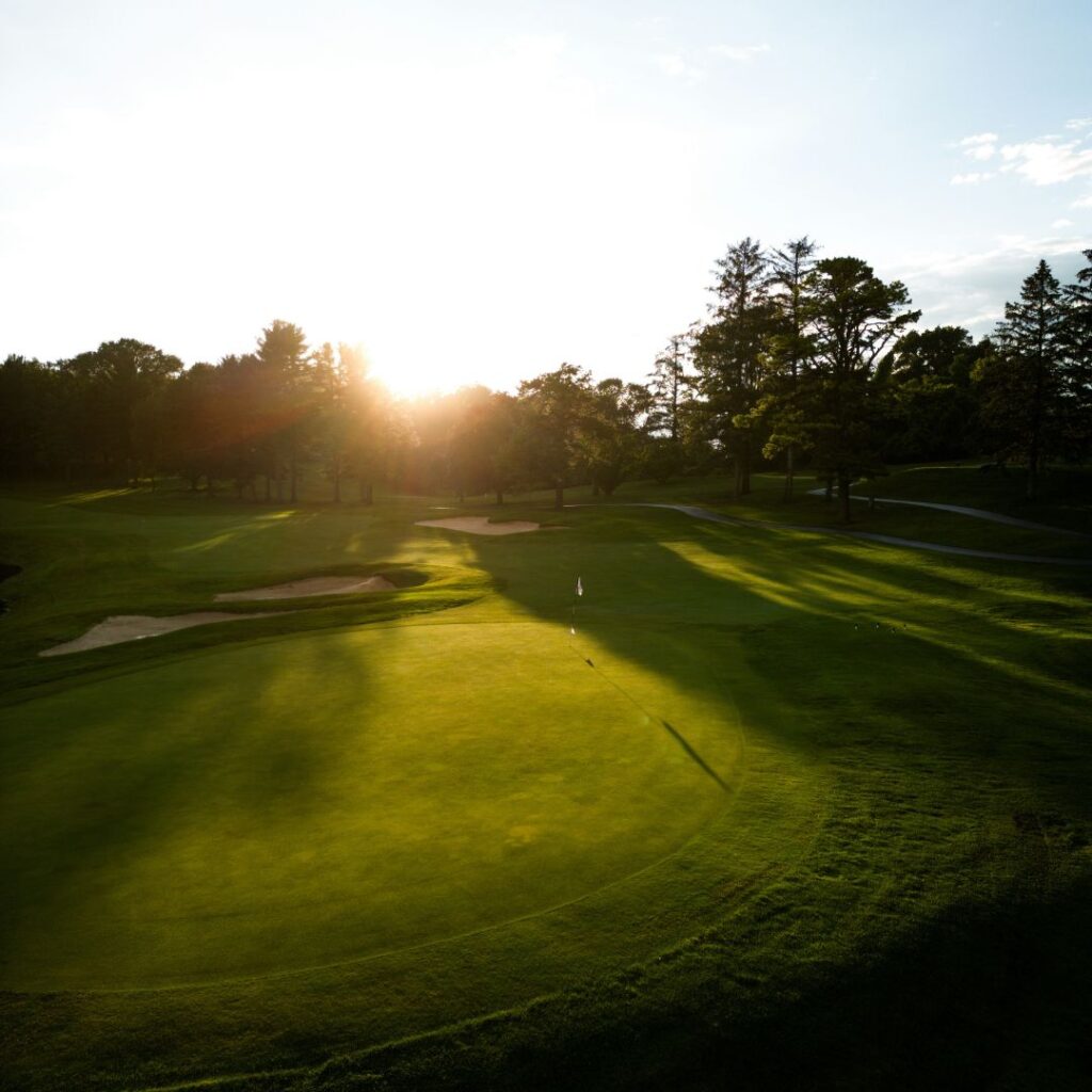 Peaceful golf course at sunset with long shadows across the green.