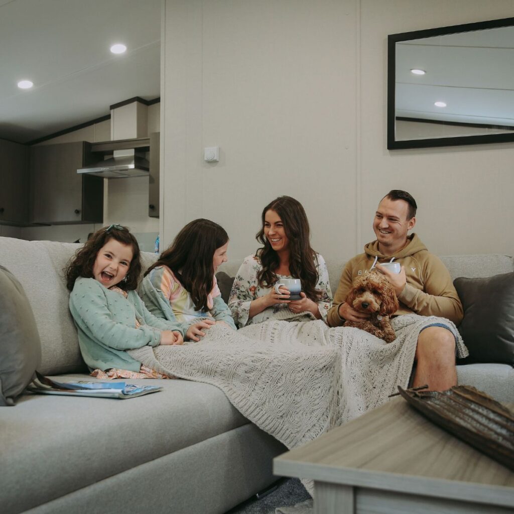 Family relaxing with their dog inside a caravan at The Beach Caravan Park