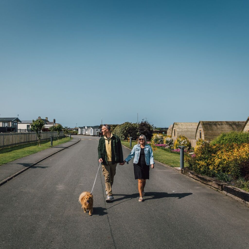 Couple walking their dog through The Beach Caravan Park