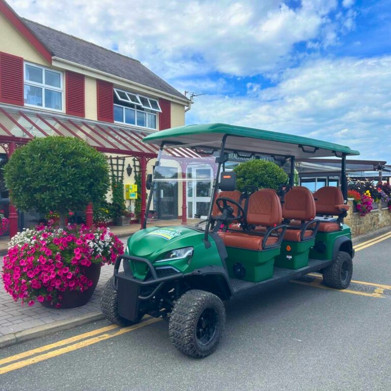 Green electric golf buggy outside reception at The Beach Caravan Park