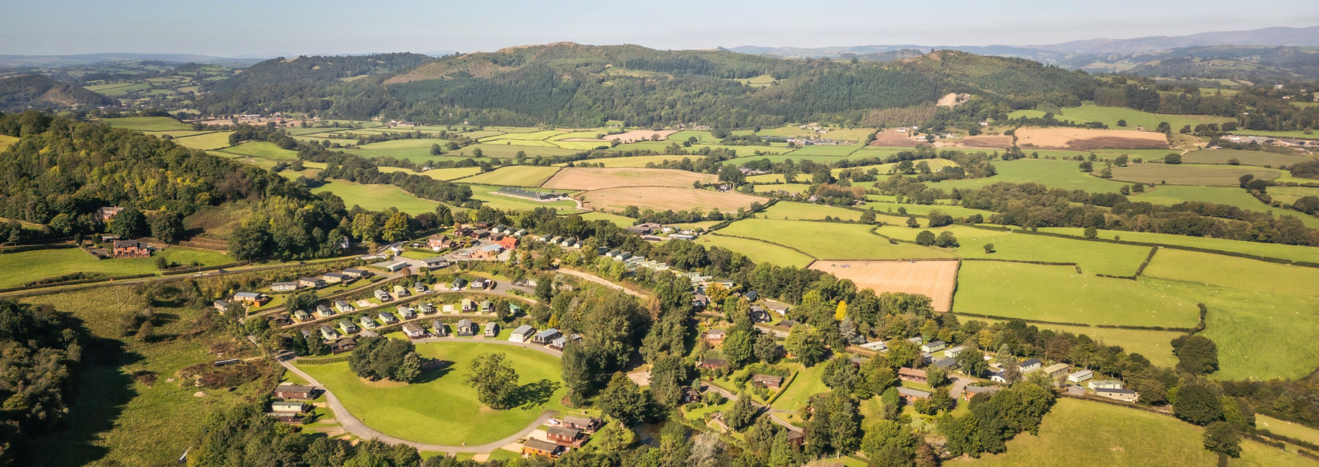 Aerial view of Valley View Holiday Park, surrounded by green fields, mature trees and rolling countryside.